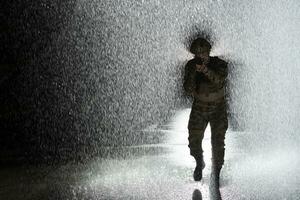 Army soldier in Combat Uniforms with an assault rifle, plate carrier and combat helmet going on a dangerous mission on a rainy night. photo