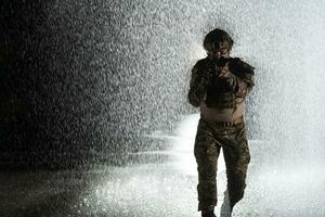 Army soldier in Combat Uniforms with an assault rifle, plate carrier and combat helmet going on a dangerous mission on a rainy night. photo