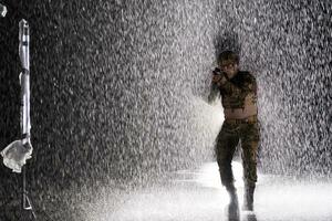 Army soldier in Combat Uniforms with an assault rifle, plate carrier and combat helmet going on a dangerous mission on a rainy night. photo