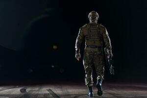 Army soldier in Combat Uniforms with an assault rifle, plate carrier and combat helmet going on a dangerous mission on a rainy night. photo