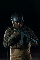 Army soldier in Combat Uniforms with an assault rifle, plate carrier and combat helmet going on a dangerous mission on a rainy night. photo