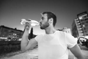 hombre bebiendo agua después de la sesión de carrera foto