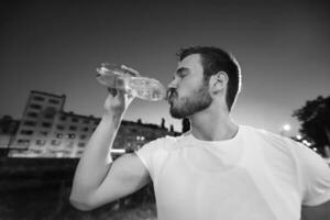 hombre bebiendo agua después de la sesión de carrera foto