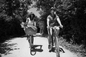 joven pareja multiétnica dando un paseo en bicicleta en la naturaleza foto