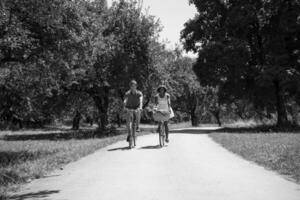 joven pareja multiétnica dando un paseo en bicicleta en la naturaleza foto