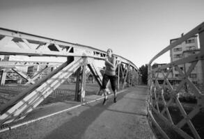 mujer corriendo por el puente en la mañana soleada foto