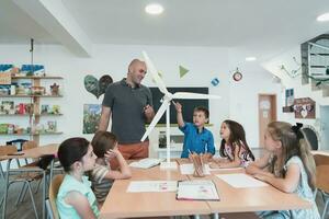 Elementary School Stem Robotics Classroom Diverse Group of Children Building and Programming windmill ecology robot concept. Together Talking and Working as a Team. Creative Robotics Engineering photo