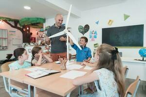 Elementary School Stem Robotics Classroom Diverse Group of Children Building and Programming windmill ecology robot concept. Together Talking and Working as a Team. Creative Robotics Engineering photo