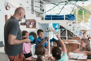 Elementary School Stem Robotics Classroom Diverse Group of Children Building and Programming windmill ecology robot concept. Together Talking and Working as a Team. Creative Robotics Engineering photo