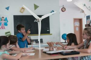 Elementary School Stem Robotics Classroom Diverse Group of Children Building and Programming windmill ecology robot concept. Together Talking and Working as a Team. Creative Robotics Engineering photo