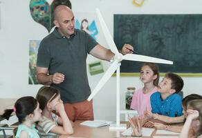 Elementary School Stem Robotics Classroom Diverse Group of Children Building and Programming windmill ecology robot concept. Together Talking and Working as a Team. Creative Robotics Engineering photo