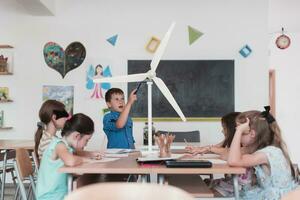 Elementary School Stem Robotics Classroom Diverse Group of Children Building and Programming windmill ecology robot concept. Together Talking and Working as a Team. Creative Robotics Engineering photo