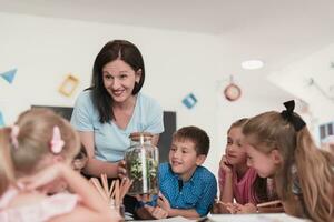 hembra profesor con niños en biología clase a elemental colegio conductible biología o botánico científico experimentar acerca de sostenible creciente plantas. aprendizaje acerca de plantas en un vaso tarro foto