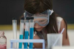 Elementary School Science Classroom Little girl Mixes Chemicals in Beakers. Children Learn with Interest photo