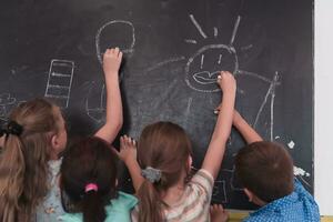 niños escribir y dibujar en el pizarra en elemental colegio mientras aprendizaje el lo esencial de educación foto