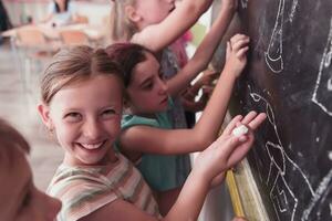 Children write and draw on the blackboard in elementary school while learning the basics of education photo