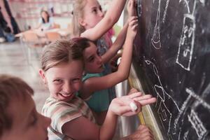 niños escribir y dibujar en el pizarra en elemental colegio mientras aprendizaje el lo esencial de educación foto