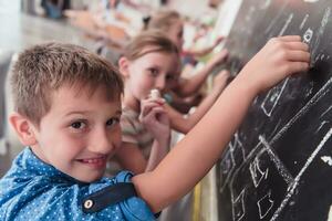 Children write and draw on the blackboard in elementary school while learning the basics of education photo