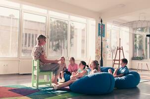 leyendo hora en elemental colegio o jardín de infancia, profesor leyendo un libro a niños en elemental colegio o jardín de infantes. selectivo atención foto