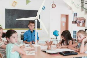 Elementary School Stem Robotics Classroom Diverse Group of Children Building and Programming windmill ecology robot concept. Together Talking and Working as a Team. Creative Robotics Engineering photo