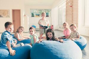 Reading time in elementary school or kindergarten, teacher reading a book to kids in elementary school or kindergaden. Selective focus photo