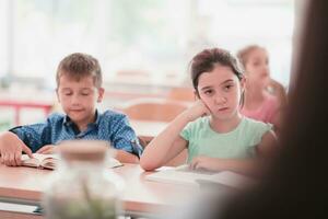 Little girls sitting in elementary school drawing on paper with their friends while sitting in a modern classroom photo