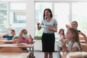 The end of the pandemic. The teacher in the school takes off the protective masks with the students photo