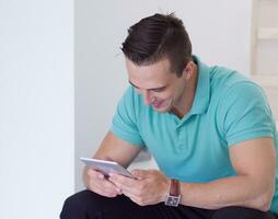 man using a tablet while sitting on the stairs at home photo