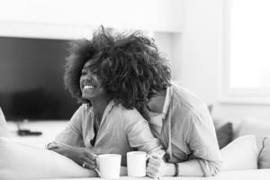 multiethnic couple sitting on sofa at home drinking coffe photo