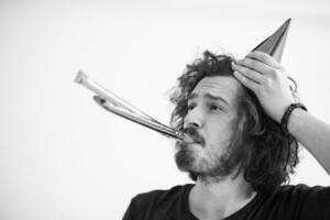 Portrait of a man in party hat blowing in whistle photo