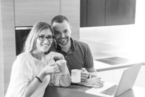 couple drinking coffee and using laptop at home photo