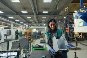 una mujer que trabaja en una fábrica de metal moderna ensambla piezas para una nueva máquina foto