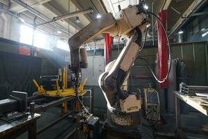 El brazo mecánico del robot de soldadura automática está trabajando en la moderna fábrica de piezas de automóviles. foto