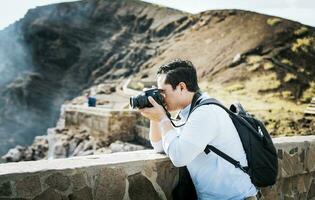 cerca arriba de turista hombre tomando fotos a un volcánico punto de vista. un turista hombre con un foto cámara tomando fotos a un punto de vista. aventurero hombre con su cámara tomando fotos a un punto de vista