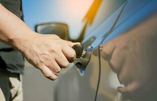 Hands with keys opening the car door. Close-up of hands opening the car door with the key. Vehicle owner opening the door with the keys. photo