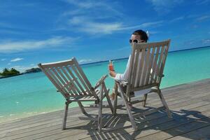 Beautiful young woman with a drink by the sea photo