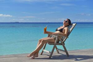 Beautiful young woman with a drink by the sea photo