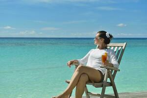 Beautiful young woman with a drink by the sea photo