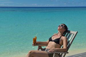 Beautiful young woman with a drink by the sea photo