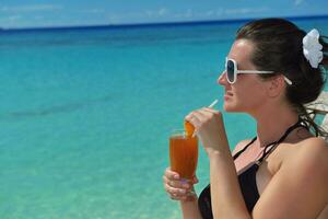 Beautiful young woman with a drink by the sea photo