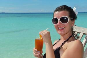 Beautiful young woman with a drink by the sea photo