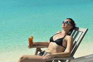 Beautiful young woman with a drink by the sea photo