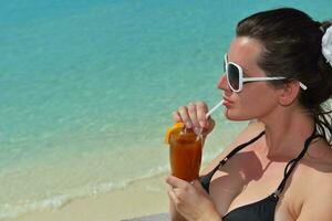 Beautiful young woman with a drink by the sea photo