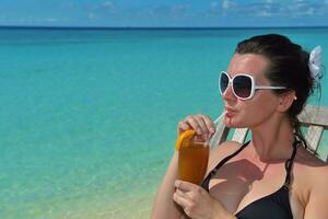 Beautiful young woman with a drink by the sea photo