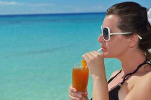 Beautiful young woman with a drink by the sea photo