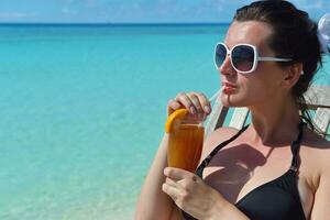 Beautiful young woman with a drink by the sea photo