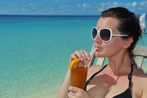 Beautiful young woman with a drink by the sea photo