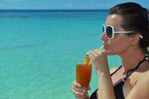 Beautiful young woman with a drink by the sea photo