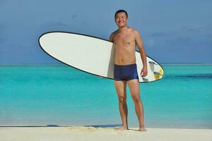 hombre con tabla de surf en la playa foto