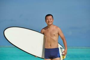 hombre con tabla de surf en la playa foto